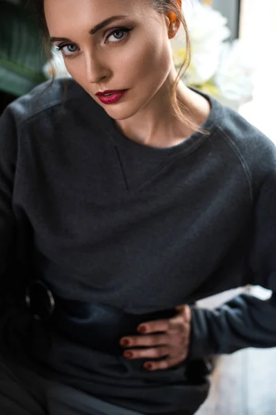Обрезанный снимок красивой нежной девушки в сером свитере, смотрящей в камеру — стоковое фото