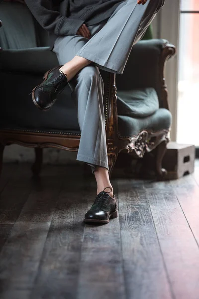 Seção baixa de menina em sapatos de couro e calças elegantes sentado na poltrona — Fotografia de Stock