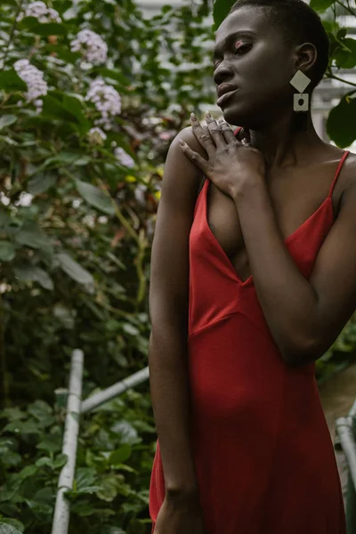 Atractiva mujer afroamericana de moda posando en jardín tropical - foto de stock