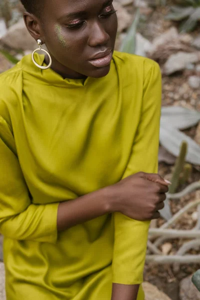 Femme afro-américaine à la mode avec un maquillage à paillettes posant en robe jaune — Photo de stock