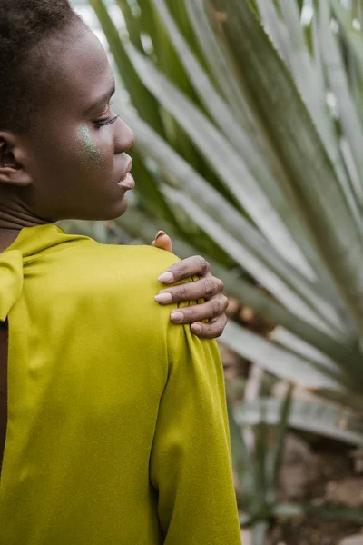 Visão traseira da bela menina americana africana elegante com maquiagem brilho posando em vestido amarelo — Fotografia de Stock