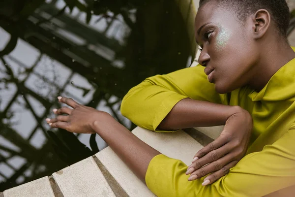 Atractiva chica afroamericana tierna con maquillaje brillo posando cerca de la piscina - foto de stock