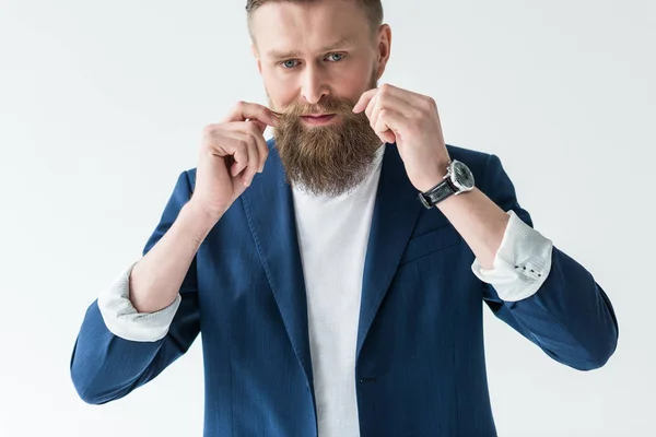 Handsome bearded man styling his mustache isolated on light background — Stock Photo