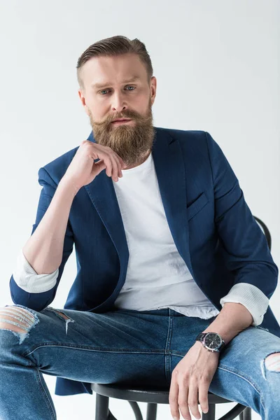 Стильний бородатий чоловік сидить на стільці ізольований на світлому фоні — стокове фото