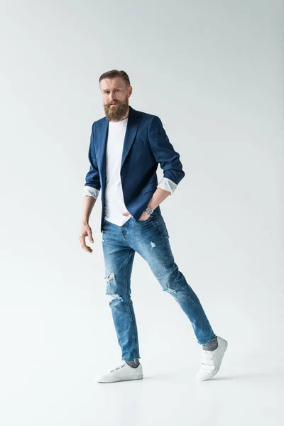 Elegante hombre barbudo en jeans y chaqueta aislada sobre fondo claro - foto de stock