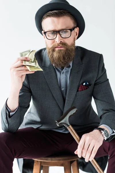 Empresario con bigote vintage y barba sosteniendo dólares aislados sobre fondo claro - foto de stock