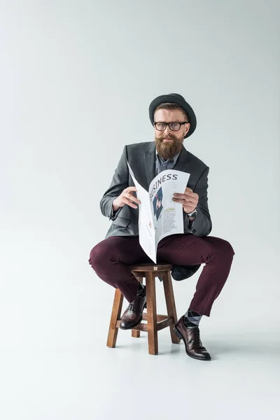 Homme d'affaires avec moustache vintage et barbe lisant un journal d'affaires assis sur un tabouret — Photo de stock