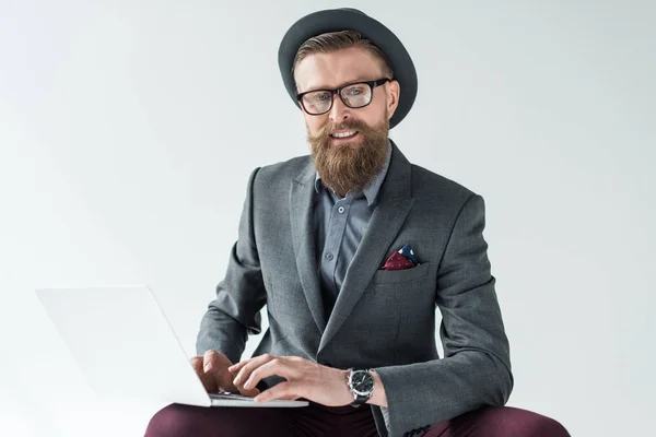 Handsome businessman in vintage style clothes working on laptop isolated on light background — Stock Photo