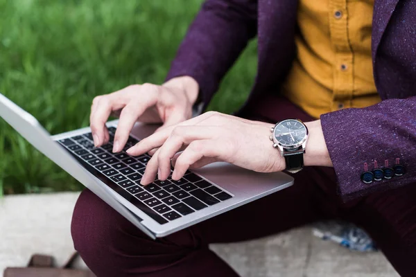 Vista de cerca de las manos masculinas con el reloj escribiendo en el teclado del ordenador portátil - foto de stock