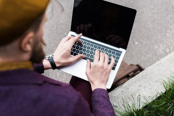 Крупным планом человек сидит на улице и печатает на клавиатуре ноутбука — стоковое фото