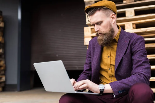 Elegante hombre de negocios barbudo escribiendo en el teclado del ordenador portátil - foto de stock