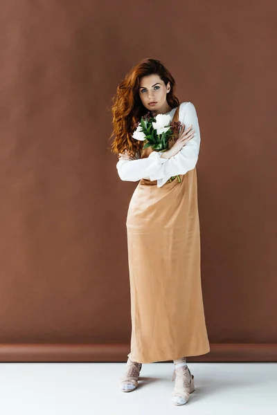 Woman with long red hair holding bouquet of flowers — Stock Photo