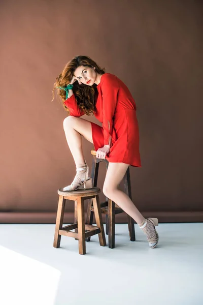 Приваблива руда жінка позує на дерев'яному стільці — стокове фото