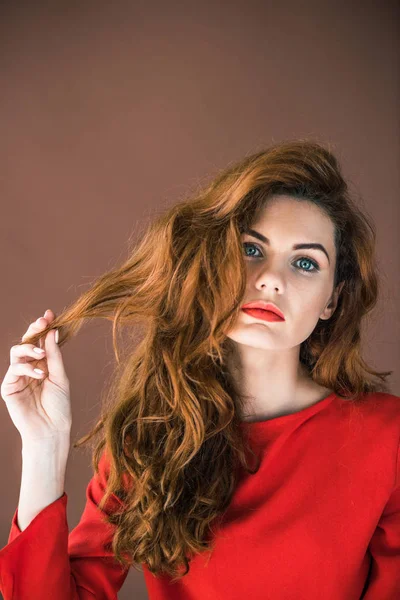 Schönes junges Mädchen spielt mit Haaren isoliert auf braunem Hintergrund — Stockfoto