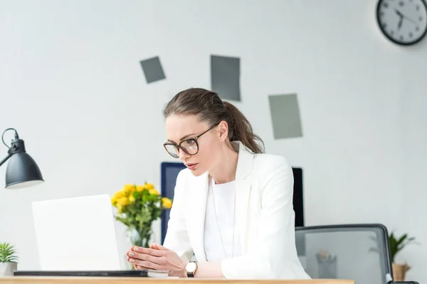 Porträt einer Geschäftsfrau mit Brille, die am Laptop am Arbeitsplatz im Büro arbeitet — Stockfoto