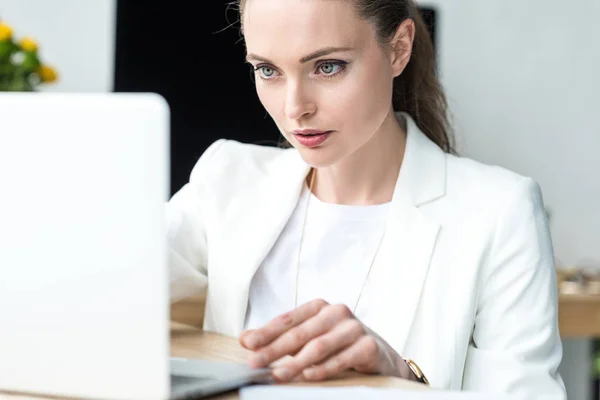 Selective focus of focused businesswoman working on laptop at workplace in office — Stock Photo