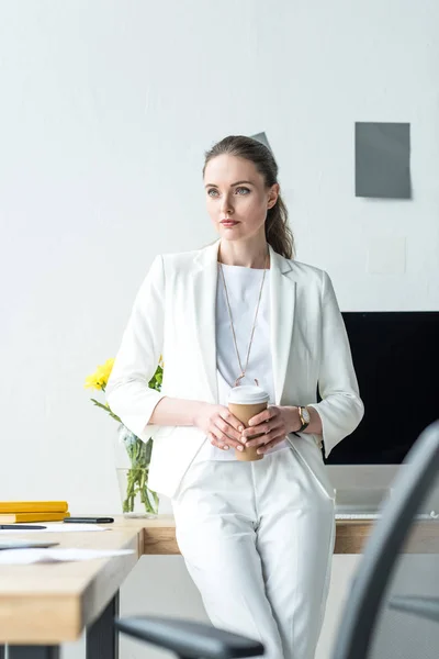 Задумчивая деловая женщина с кофе идти стоя на рабочем месте в офисе — стоковое фото