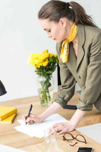 Attraktive stilvolle Geschäftsfrau, die am Arbeitsplatz Notizen macht — Stockfoto