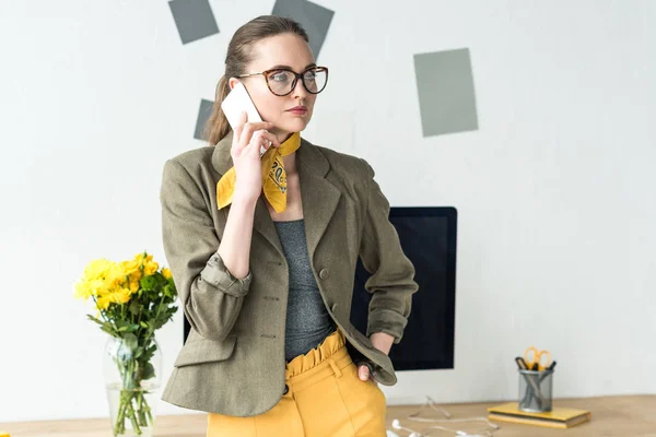 Schöne stylische Geschäftsfrau, die per Smartphone spricht und im Büro wegschaut — Stockfoto
