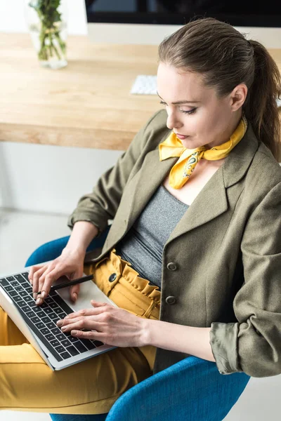 Vista de ángulo alto de la mujer de negocios elegante usando el ordenador portátil en la oficina - foto de stock