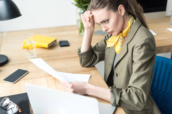 Vista ad alto angolo di focalizzata donna d'affari in possesso di carta mentre seduto sul posto di lavoro — Foto stock