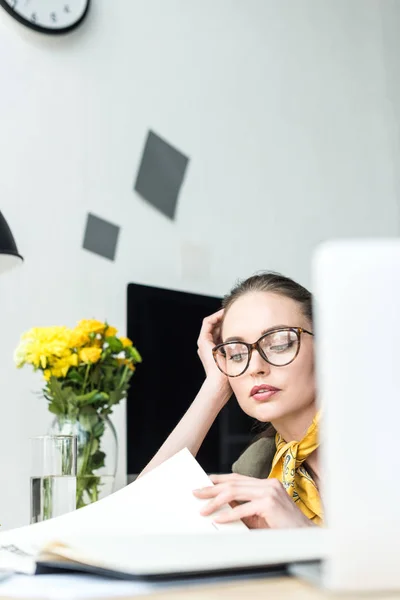Selective focus of stylish businesswoman in eyeglasses reading business magazine in office — Stock Photo
