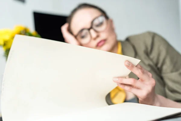 Nahaufnahme einer gelangweilten Geschäftsfrau, die am Arbeitsplatz Buch liest — Stockfoto