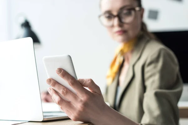 Visão de perto de empresária usando laptop e smartphone no local de trabalho — Fotografia de Stock