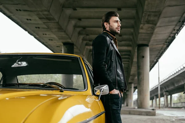 Vue latérale de l'homme élégant debout près de voiture rétro jaune et regardant loin — Photo de stock