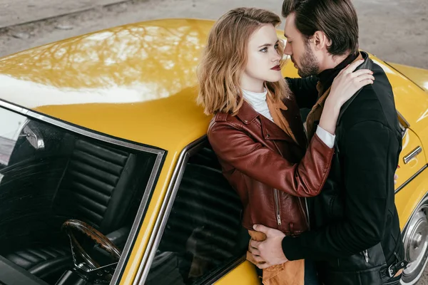 Vista de ángulo alto de sensual pareja joven abrazándose cerca de coche clásico amarillo — Stock Photo