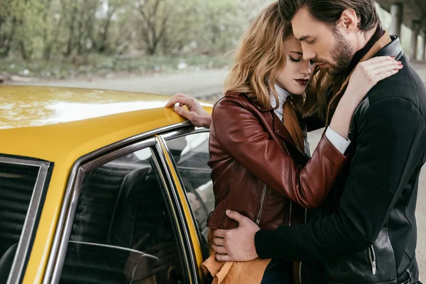 Sensual jovem casal abraçando perto de amarelo à moda antiga automóvel — Fotografia de Stock