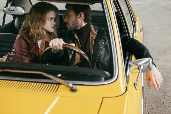 Blick durch die Windschutzscheibe eines jungen Paares, das sich im gelben Auto anschaut — Stockfoto