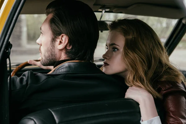 Vue arrière de élégant jeune couple assis ensemble dans l'automobile à l'ancienne — Photo de stock