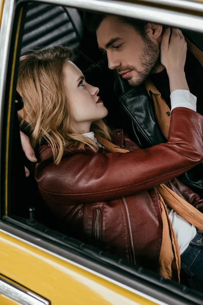 Beau jeune couple étreignant et se regardant dans la voiture — Photo de stock