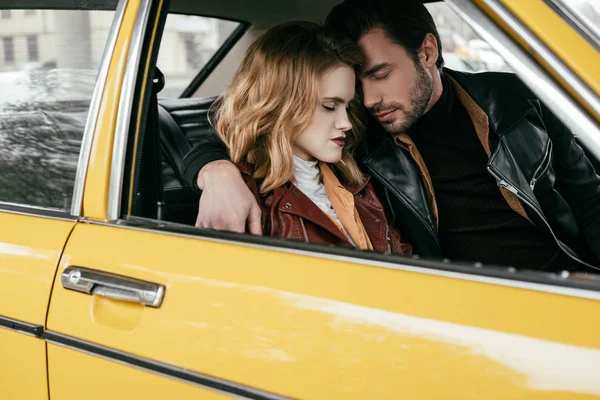 Schönes zartes junges Paar mit geschlossenen Augen, das sich im gelben Auto umarmt — Stockfoto