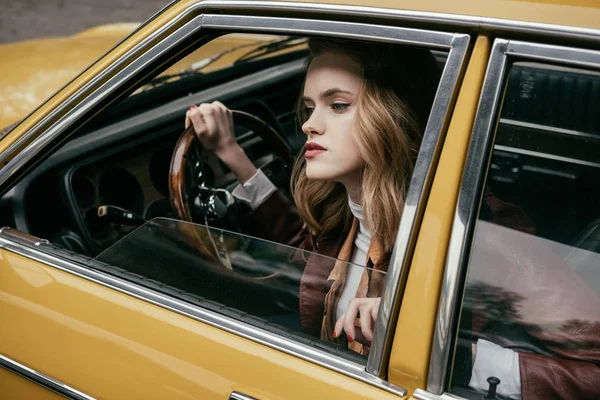 Привлекательная стильная девушка сидит в теро-машине и смотрит в сторону — стоковое фото