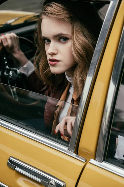 Vista de cerca de la chica mirando a la cámara mientras está sentado en el coche clásico - foto de stock