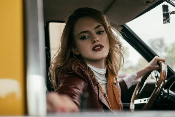 Вибірковий фокус привабливої дівчини, що тримає кермо класичного автомобіля — стокове фото