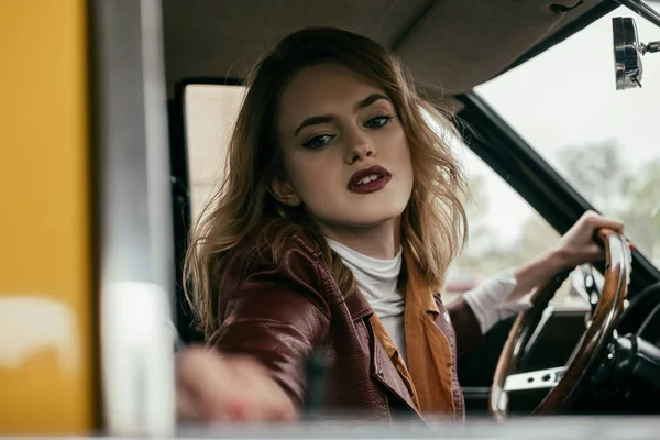 Selective focus of attractive girl holding steering wheel of classic car — Stock Photo