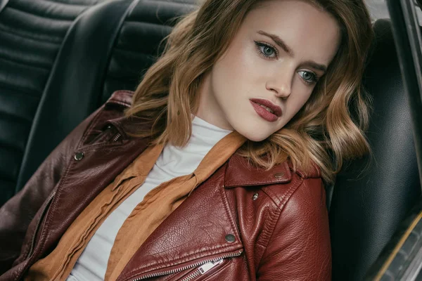 Pensive young woman sitting in car and looking away — Stock Photo