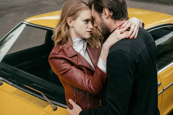 Belo sensual jovem casal abraçando perto de amarelo à moda antiga carro — Stock Photo