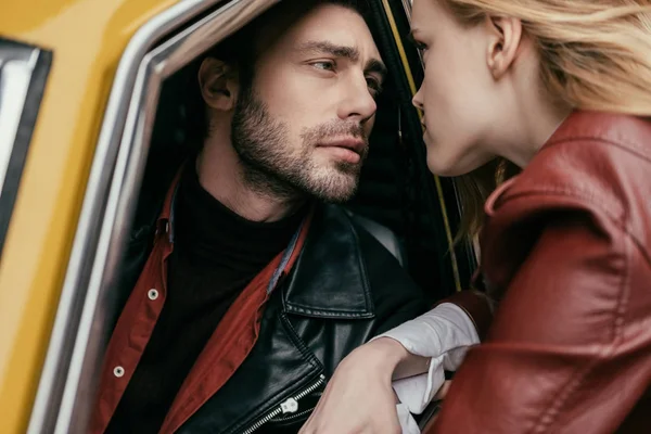 Élégant jeune couple amoureux regardant les uns les autres par la fenêtre de la voiture — Photo de stock