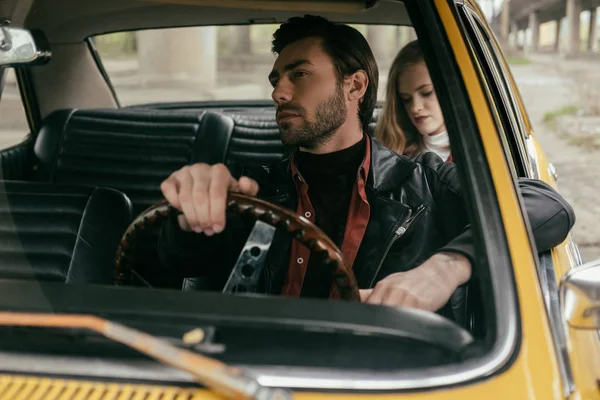 Bonito jovem condução retro carro e namorada sentado atrás — Fotografia de Stock