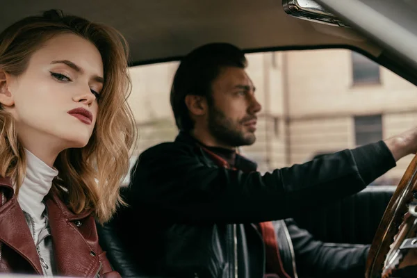 Atractiva chica con estilo mirando a la cámara mientras novio guapo conducir coche — Stock Photo