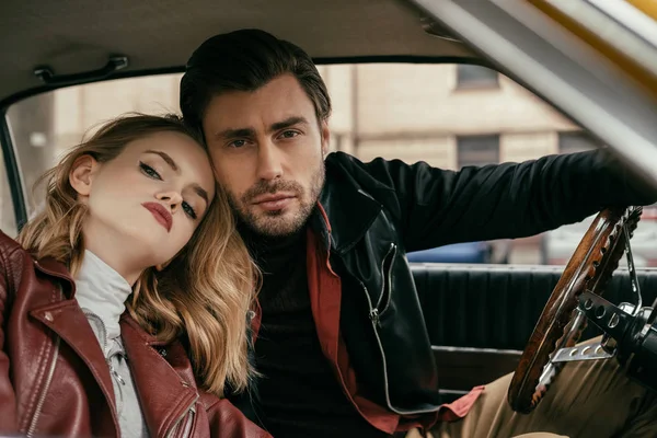 Hermosa pareja joven y elegante sentado juntos y mirando a la cámara en el coche — Stock Photo