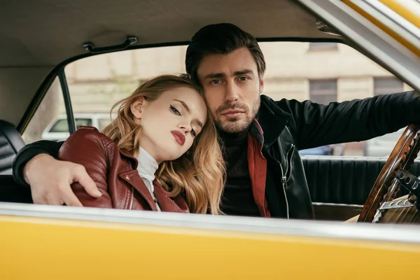 Schönes stylisches junges Paar umarmt und schaut in die Kamera im Auto — Stockfoto