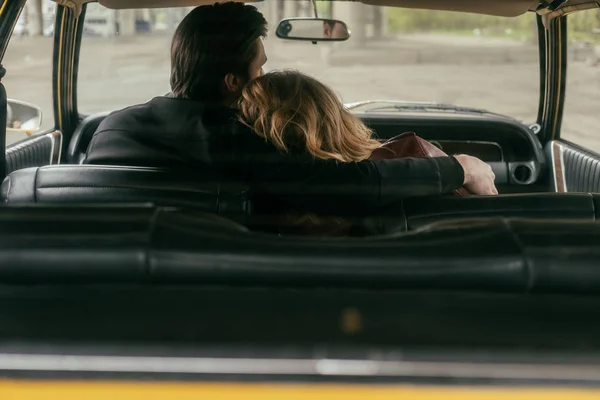 Back view of young couple in love embracing while sitting together in car — Stock Photo