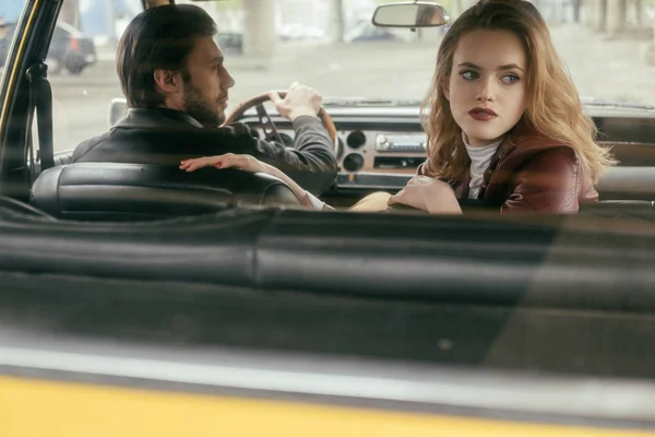 Man driving retro car and looking at beautiful girlfriend — Stock Photo