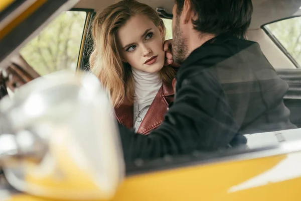 Stylish young couple looking at each other while sitting together in car — Stock Photo