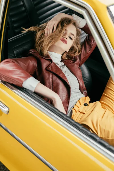 Hochwinkelaufnahme einer stilvollen jungen Frau, die in einem Oldtimer sitzt und in die Kamera schaut — Stockfoto